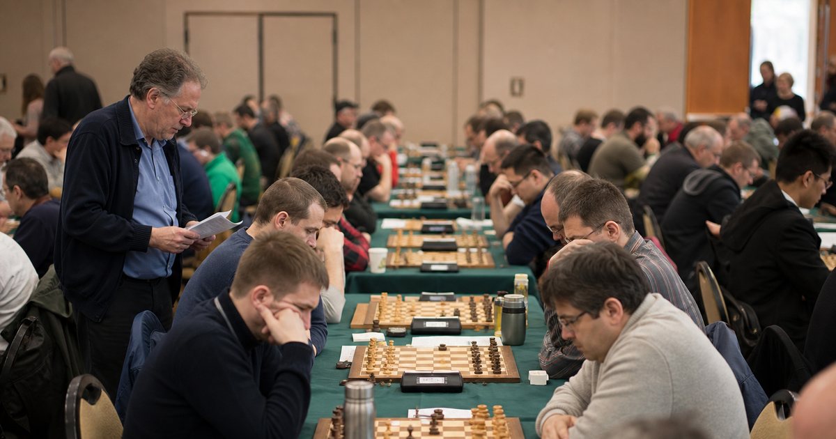 Large community hall with rows of long tables where pairs of players compete at board games, players leaning over their boards in concentration, a tournament director walking the aisle with a stack of pairing cards, warm indoor light
